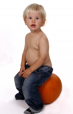 young boy seated on a pumpkin
