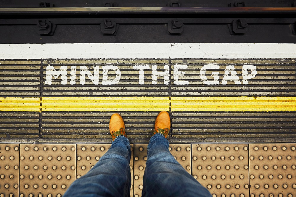 person standing on train platform with words mind the gap